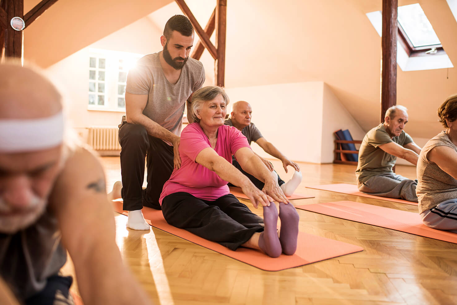 Photo of man as caregiver assisting elderly woman at yoga through a Long-term Care Job